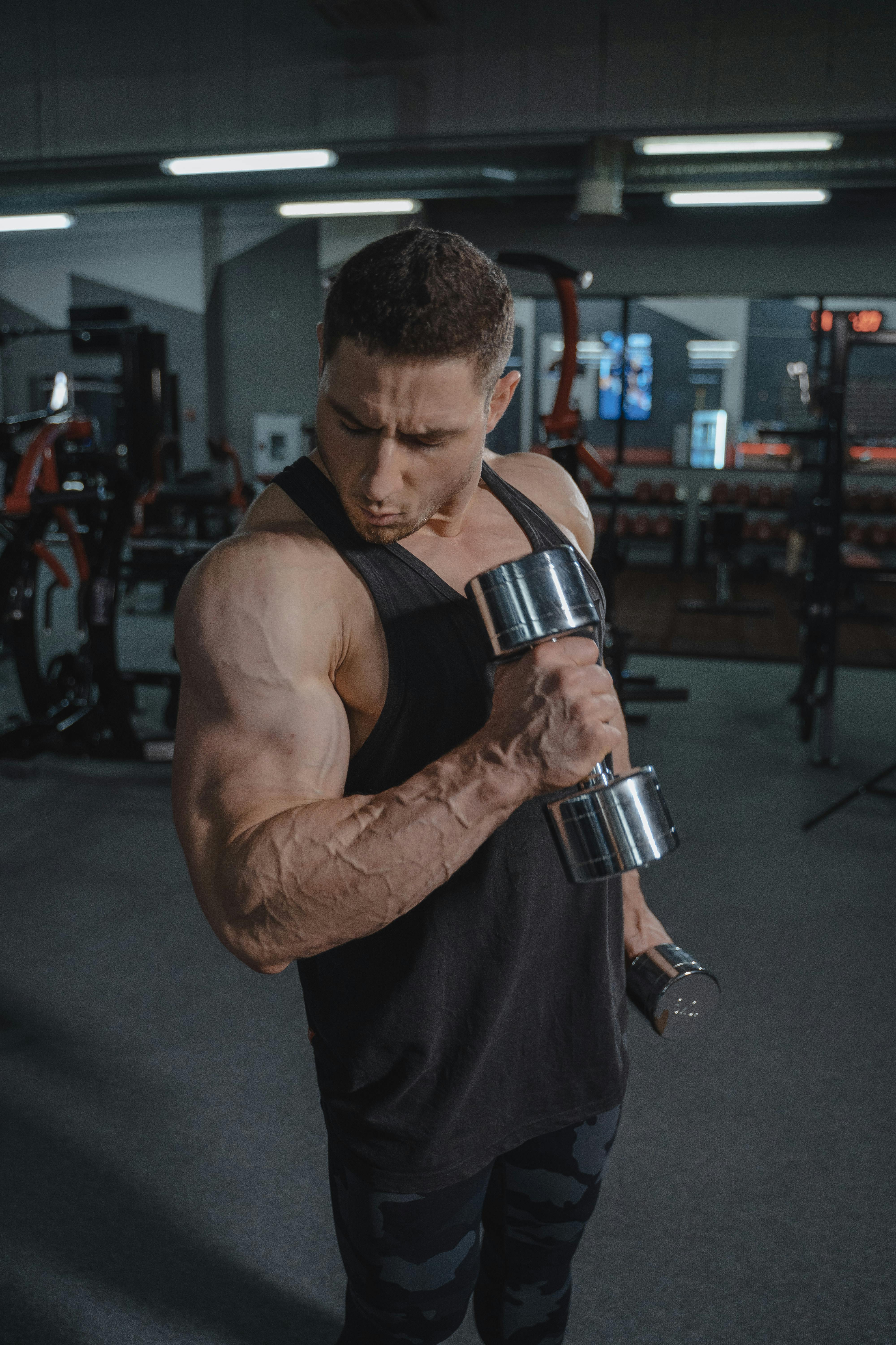 A muscular man lifting dumbbells during an intense workout session at the gym.